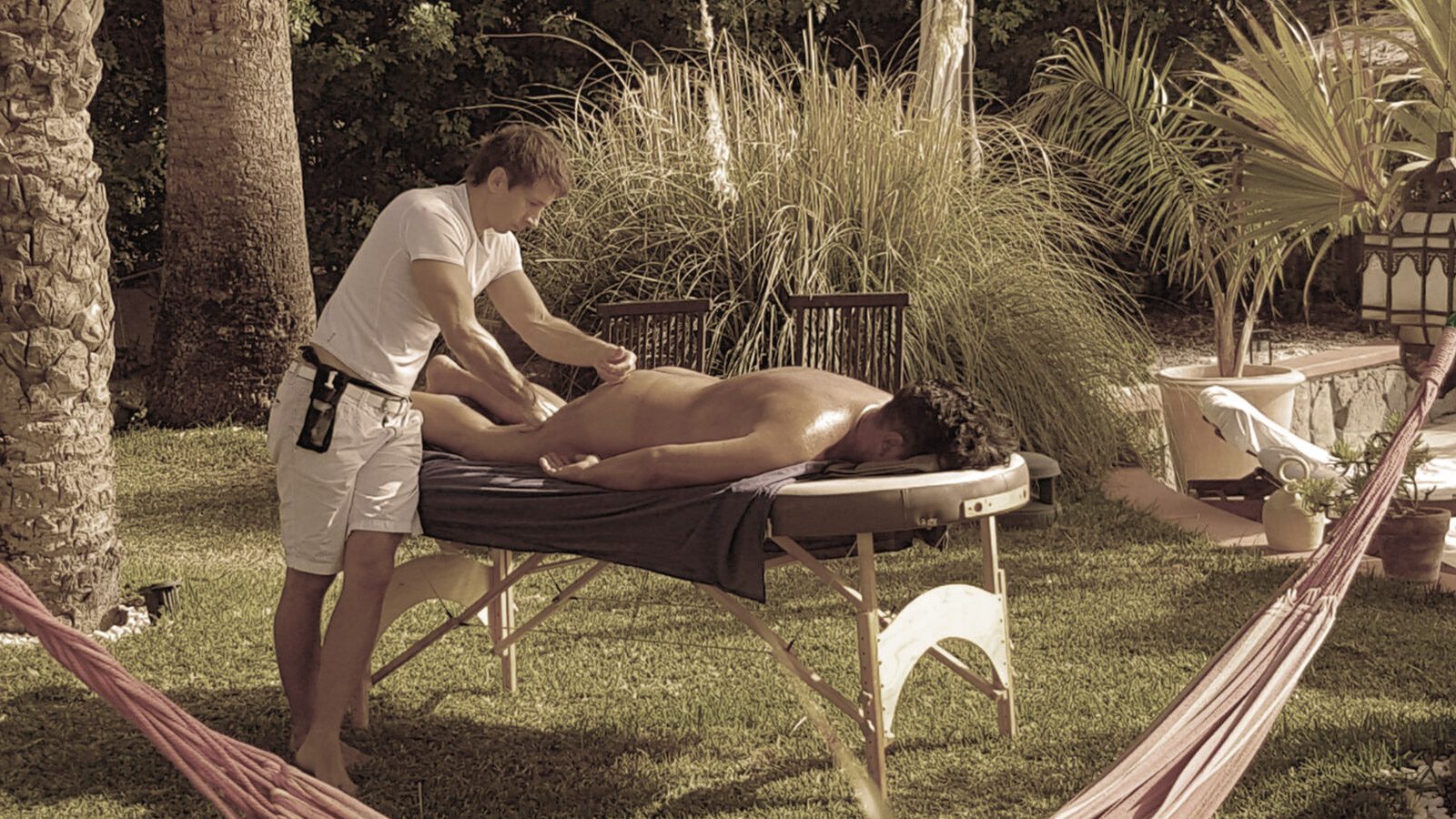An outdoor massage on the grass between the palms in a garden in Maspalomas, Gran Canaria, a hammock in the foreground